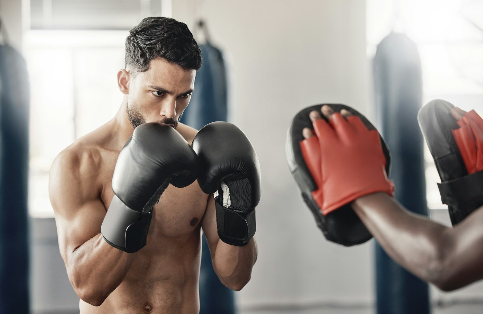 Boxing gym, fighting pad and man training with athlete coach for a fitness cardio exercise session.